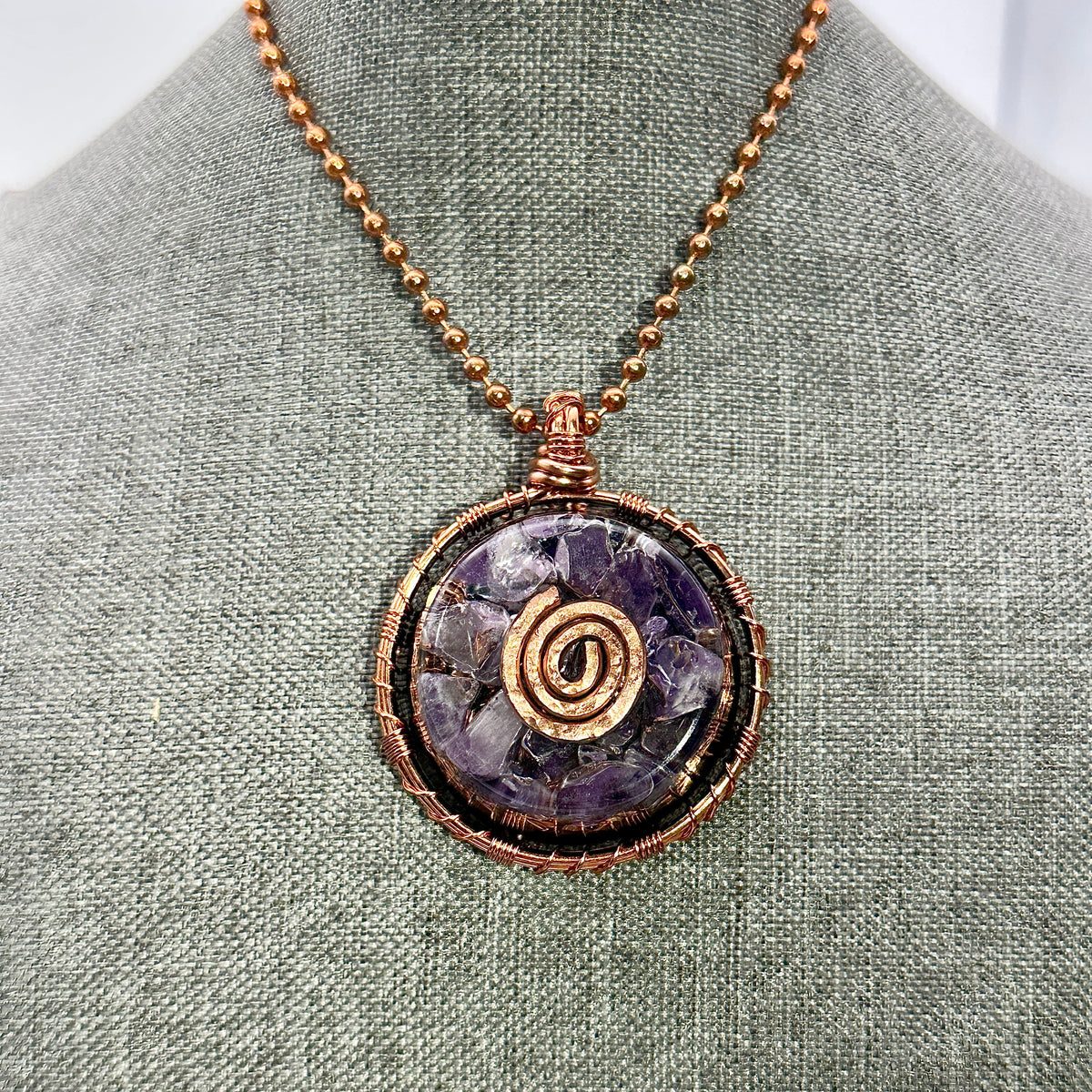 Necklace with a purple stone pendant on a gray fabric background